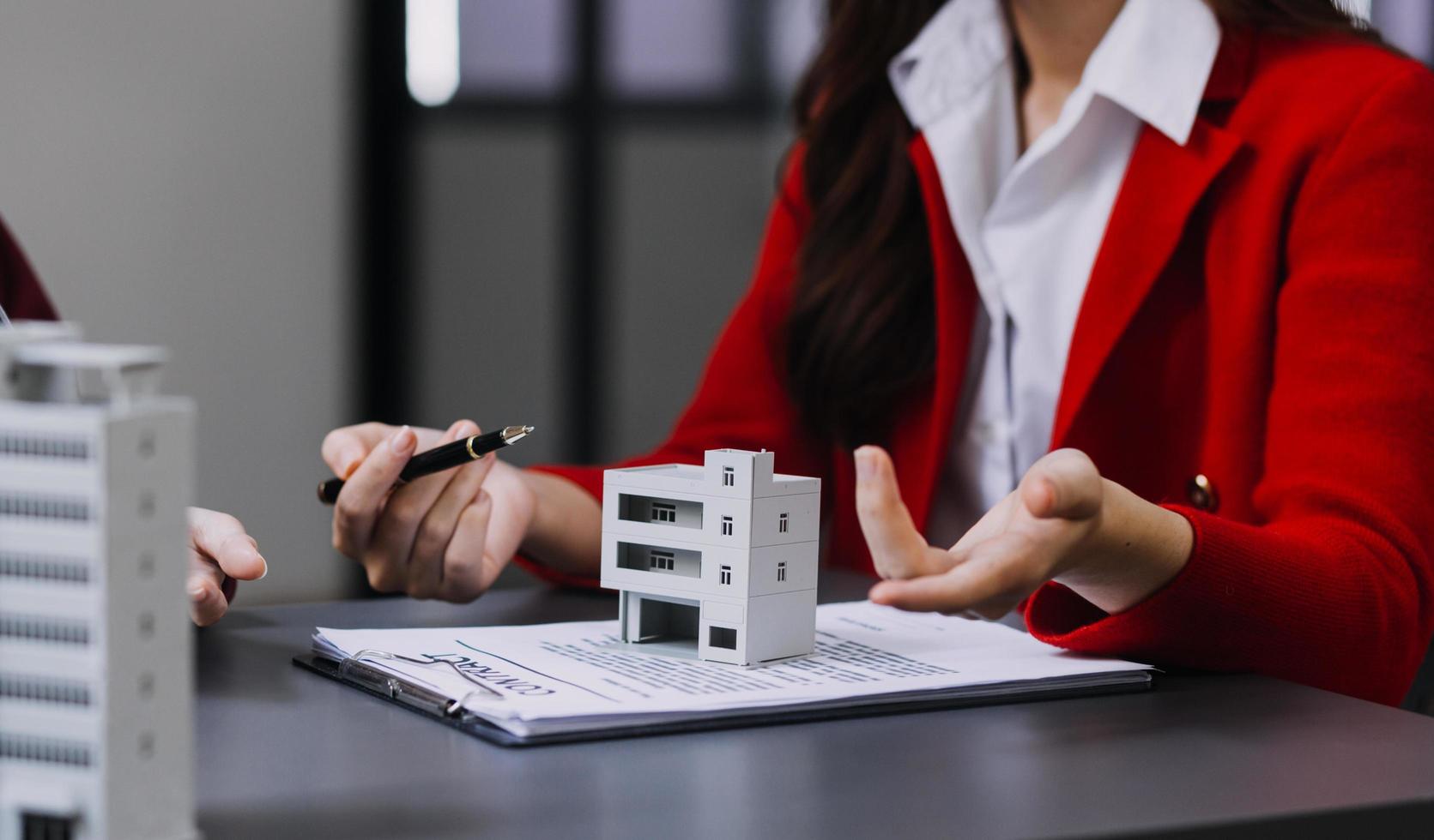 bespreking met een makelaar, huismodel met makelaar en klant bespreken voor het contract om onroerend goed of onroerend goed te kopen, een verzekering of lening af te sluiten. foto