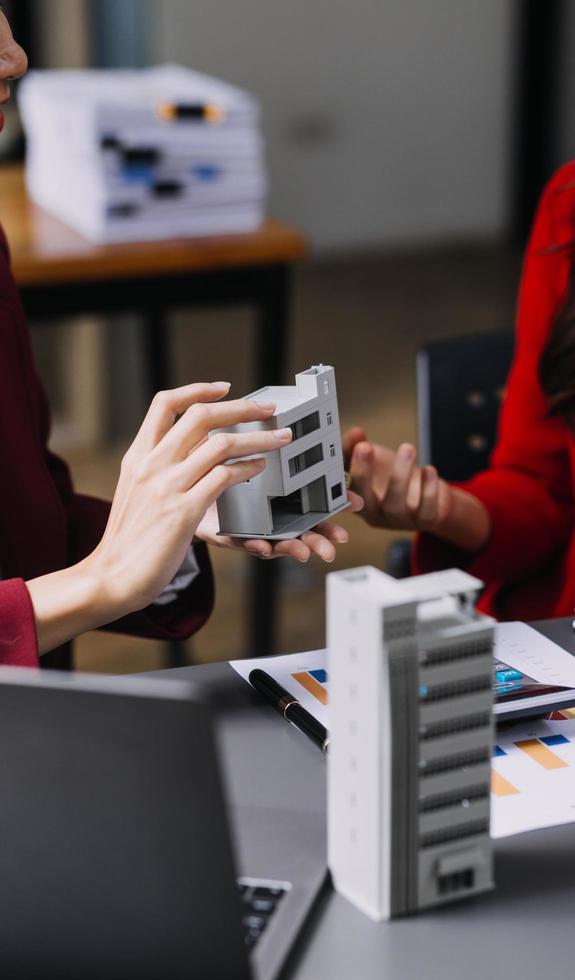 bespreking met een makelaar, huismodel met makelaar en klant bespreken voor het contract om onroerend goed of onroerend goed te kopen, een verzekering of lening af te sluiten. foto