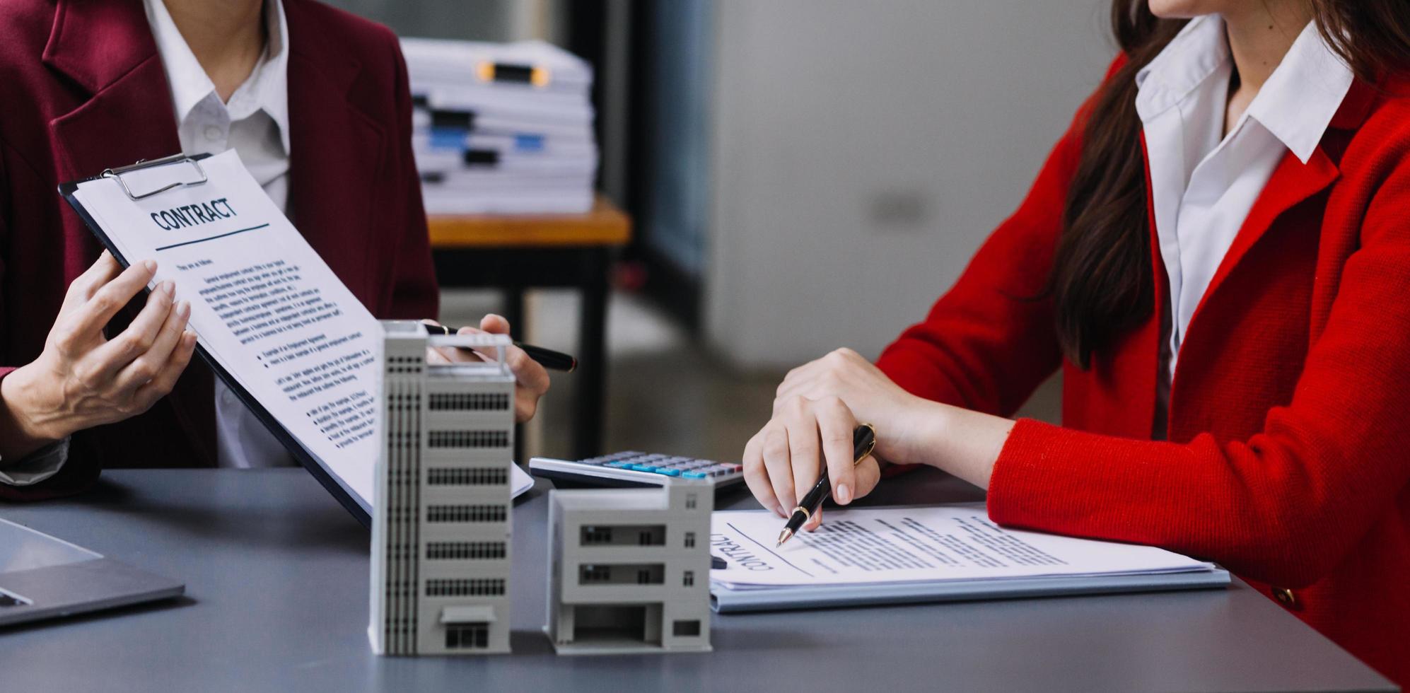 bespreking met een makelaar, huismodel met makelaar en klant bespreken voor het contract om onroerend goed of onroerend goed te kopen, een verzekering of lening af te sluiten. foto