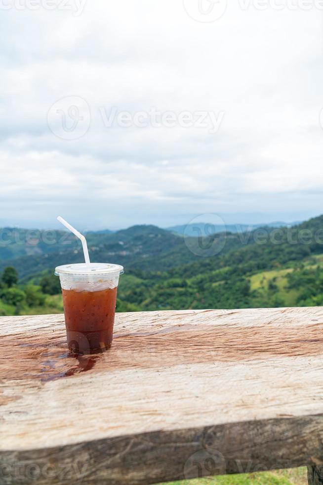 americano koffie Aan hout tafel met berg heuvel visie achtergrond foto