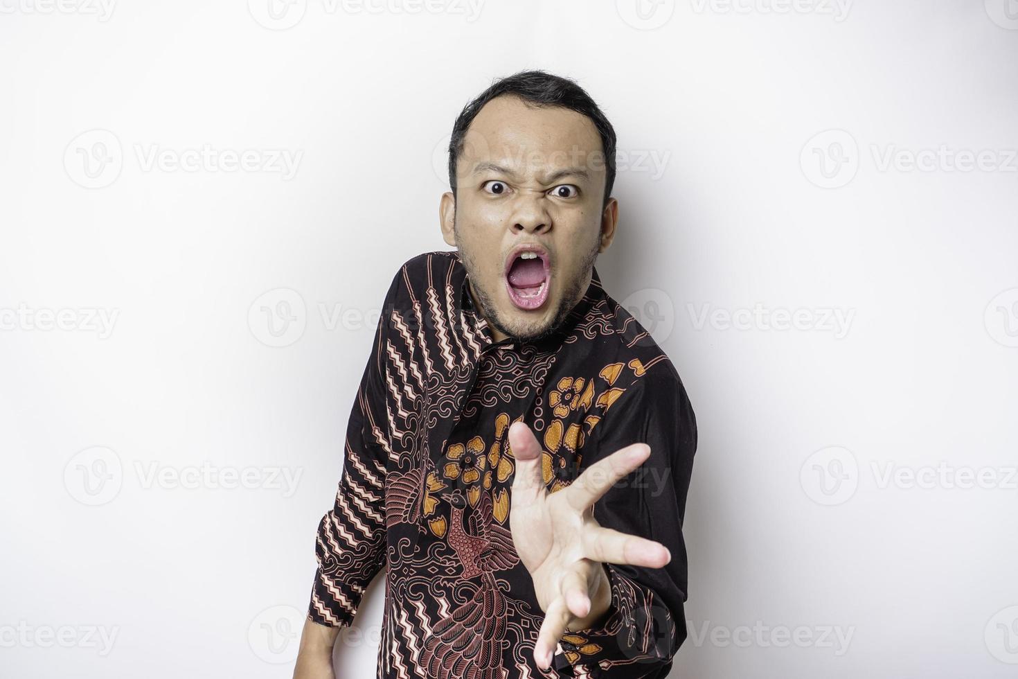 de boos en boos gezicht van Aziatisch Mens in batik overhemd geïsoleerd wit achtergrond. foto