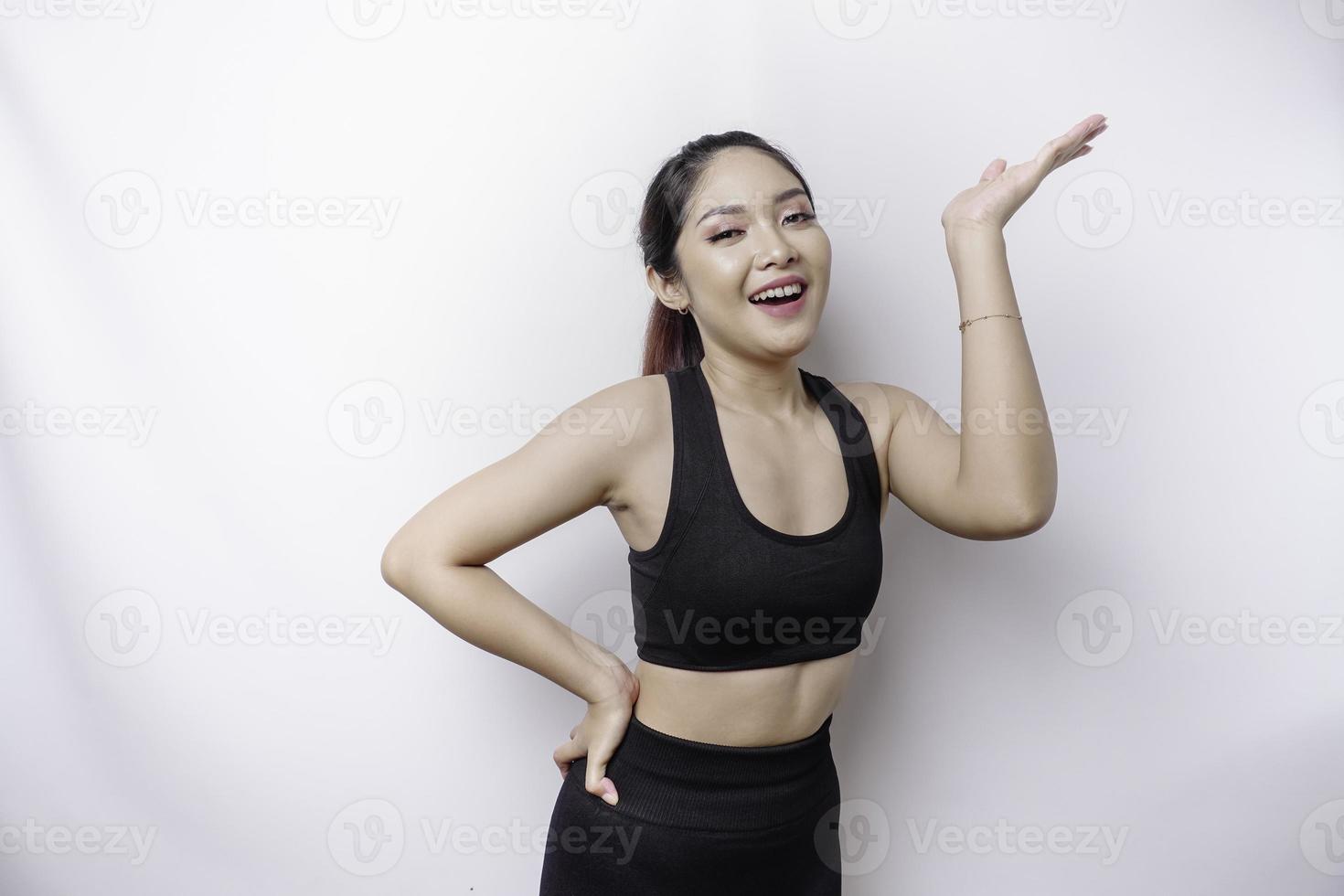 opgewonden Aziatisch sportief vrouw vervelend sportkleding richten Bij de kopiëren ruimte Aan top van haar, geïsoleerd door wit achtergrond foto