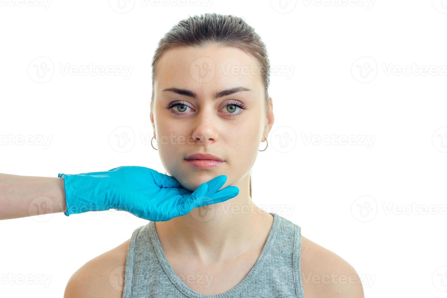 een jong meisje gehouden kin in blauw handschoen in de schoonheid salon foto