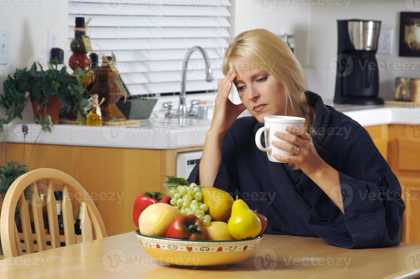 vrouw Holding hoofd in keuken foto