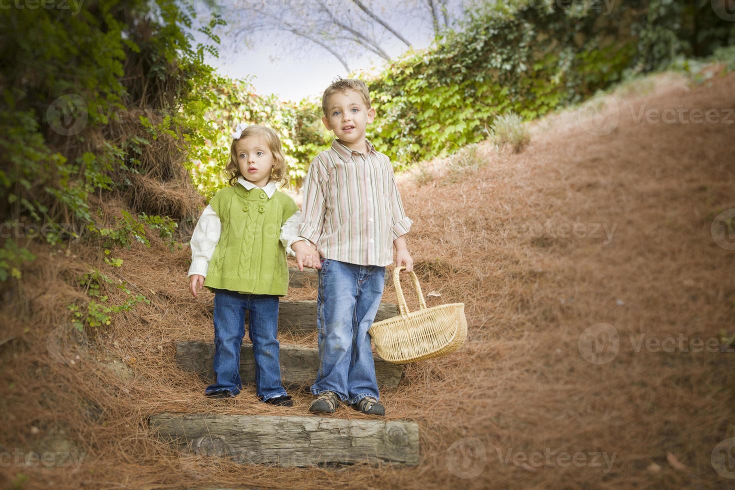 twee kinderen wandelen naar beneden hout stappen met mand buiten. foto