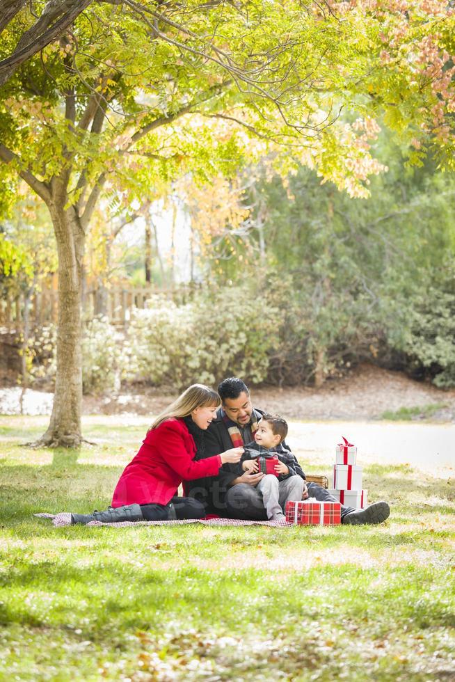 gemengd ras familie genieten van Kerstmis cadeaus in de park samen foto