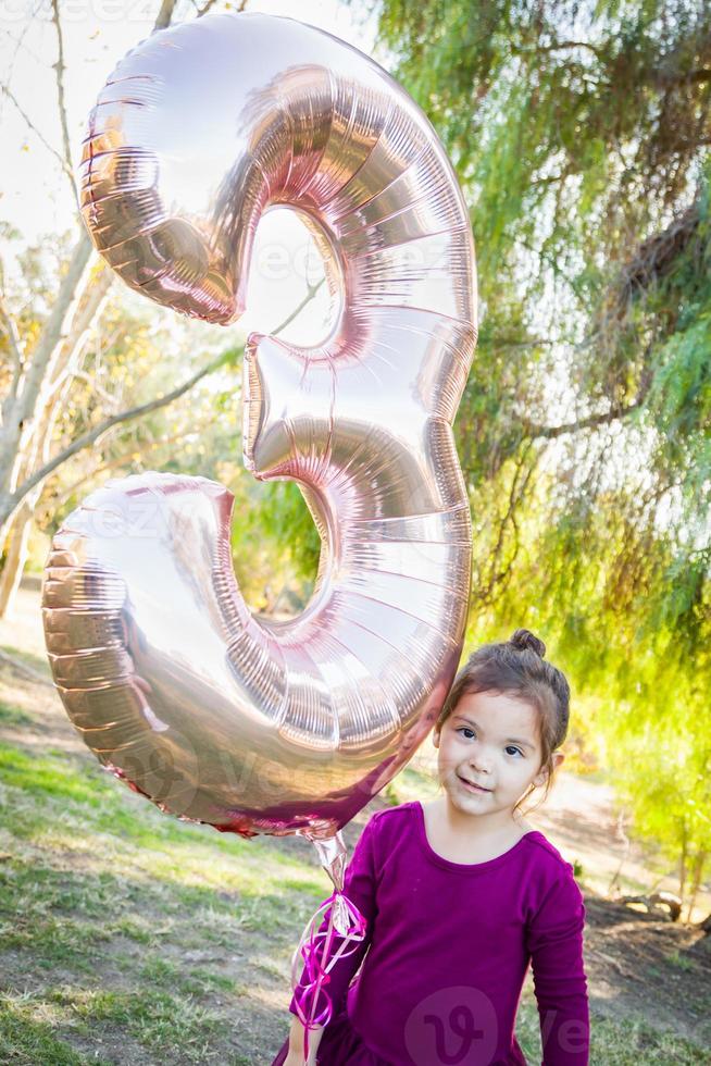 schattig baby meisje spelen met aantal drie mylar ballon buitenshuis foto