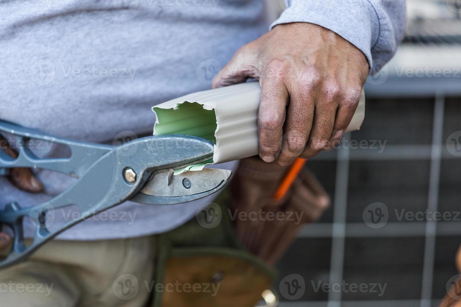 arbeider snijdend aluminium regen goot met zwaar scharen foto