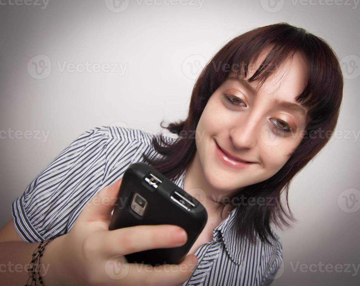 glimlachen brunette vrouw gebruik makend van cel telefoon foto