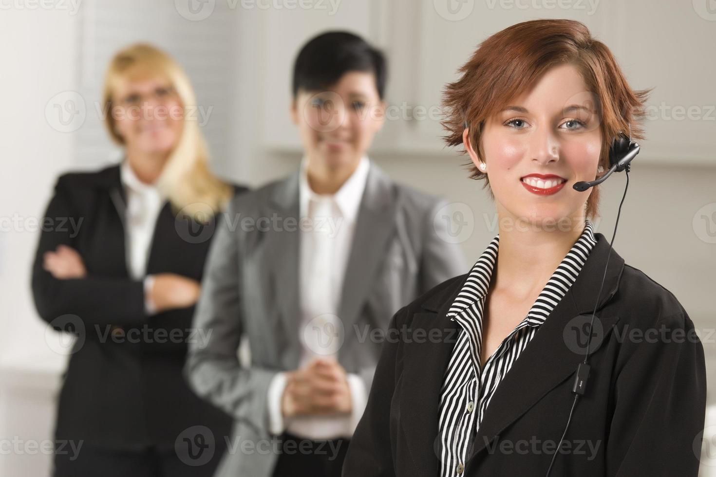 mooi rood haren zakenvrouw met koptelefoon en collega's foto