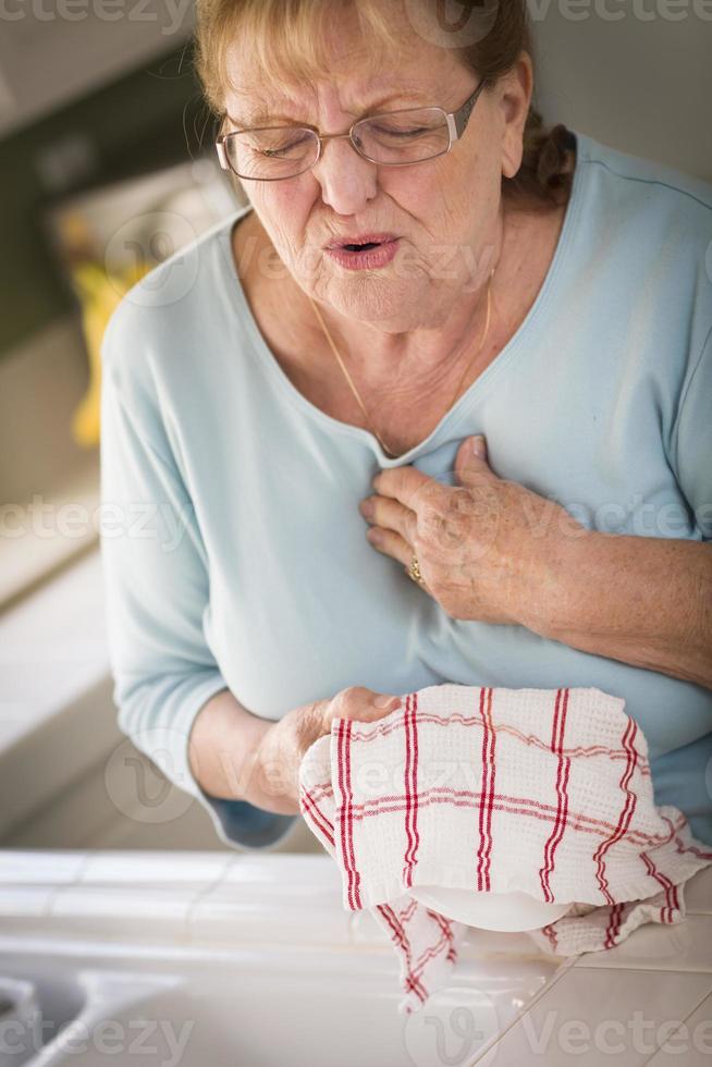 senior volwassen vrouw Bij wastafel met borst pijnen foto