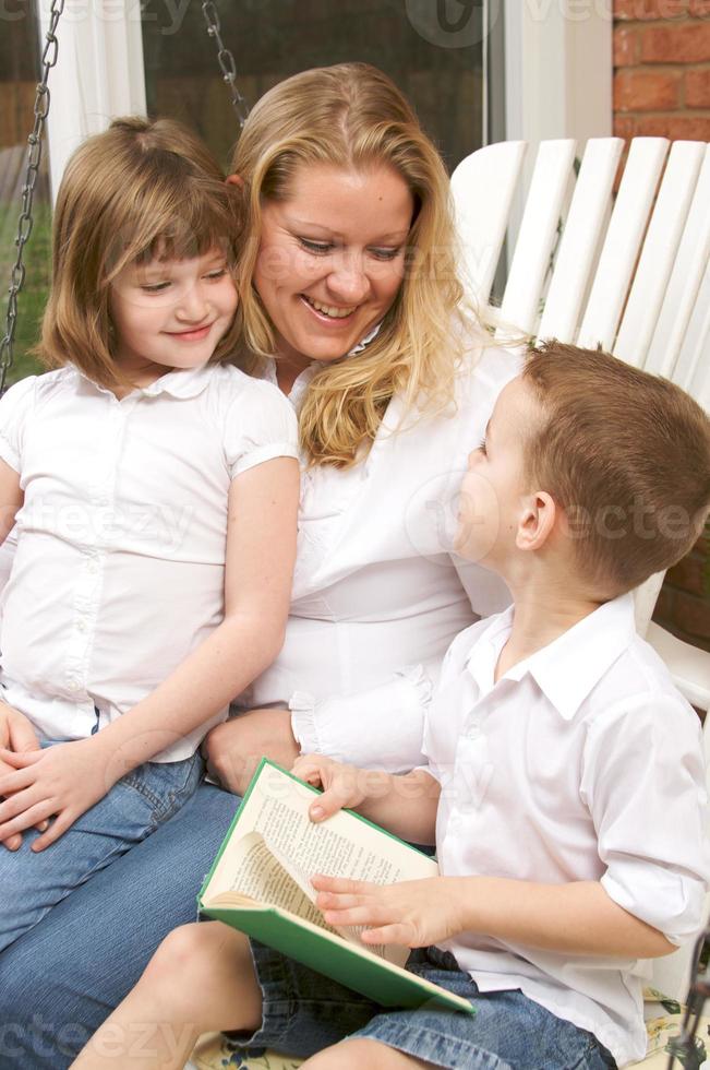 jong jongen leest naar zijn moeder en zus foto