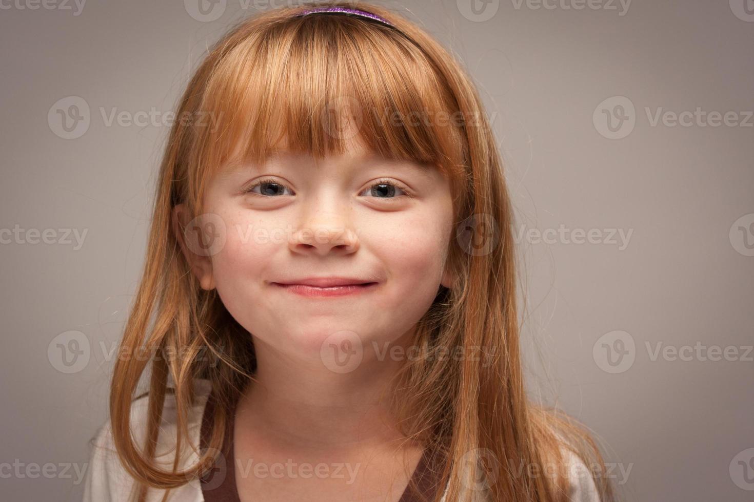 pret portret van een aanbiddelijk rood haren meisje Aan grijs foto