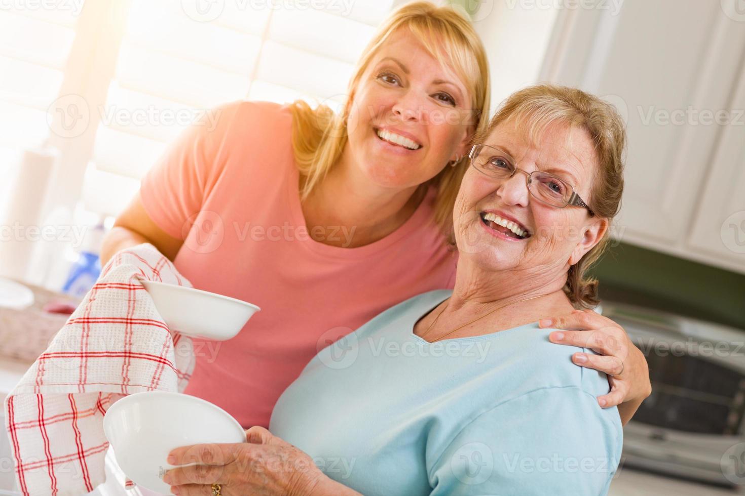 portret van glimlachen senior volwassen vrouw en jong dochter Bij wastafel in keuken foto