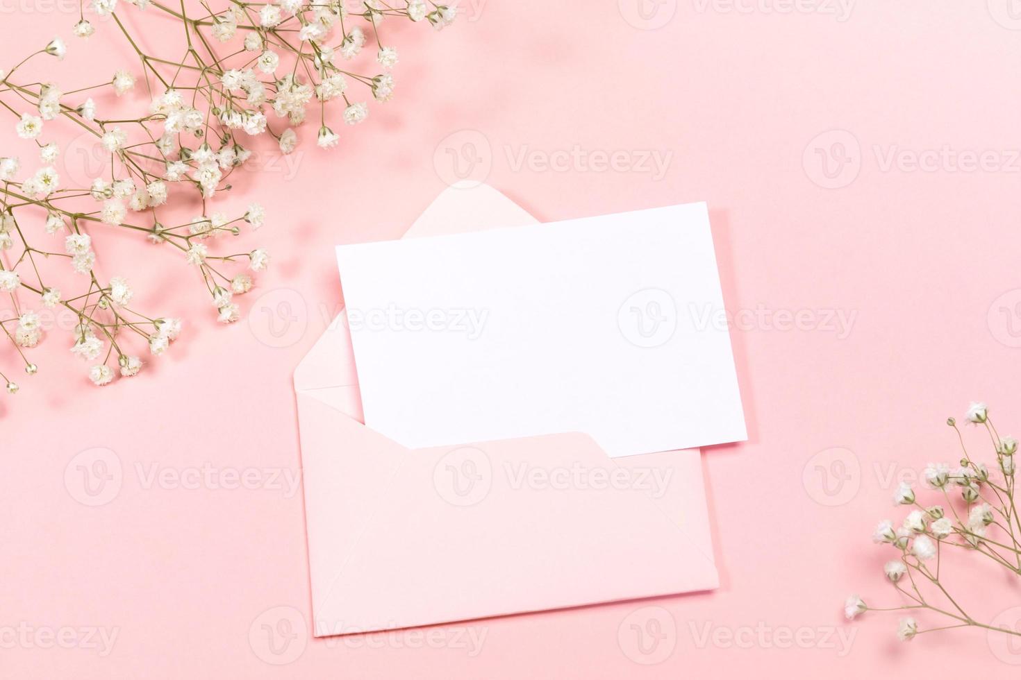 pastel roze feestelijk lay-out met envelop, leeg vel, wit gypsophila bloemen. kopiëren ruimte voor tekst. bespotten omhoog. foto