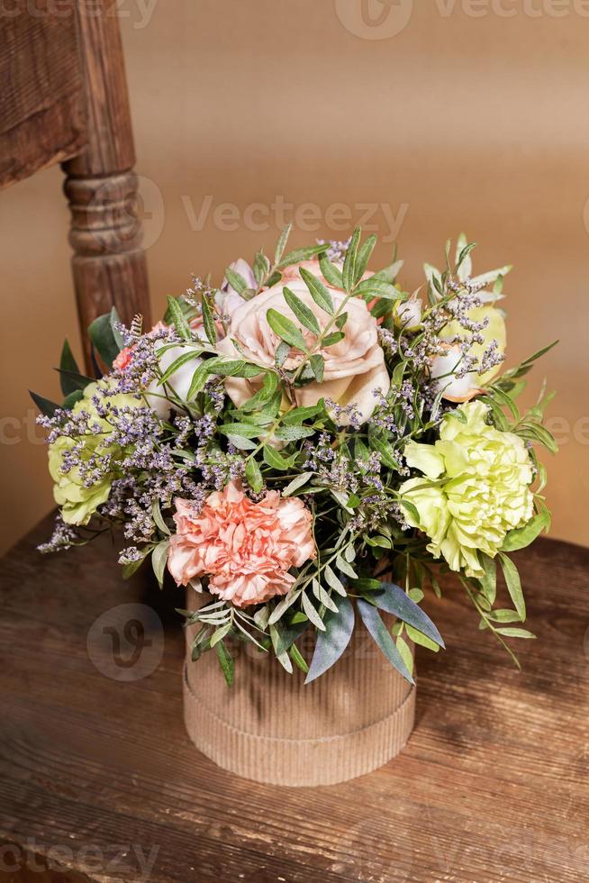 ecologisch vakantie samenstelling met bloemen boeket in diy karton vaas staand Aan oud houten stoel Aan beige. foto