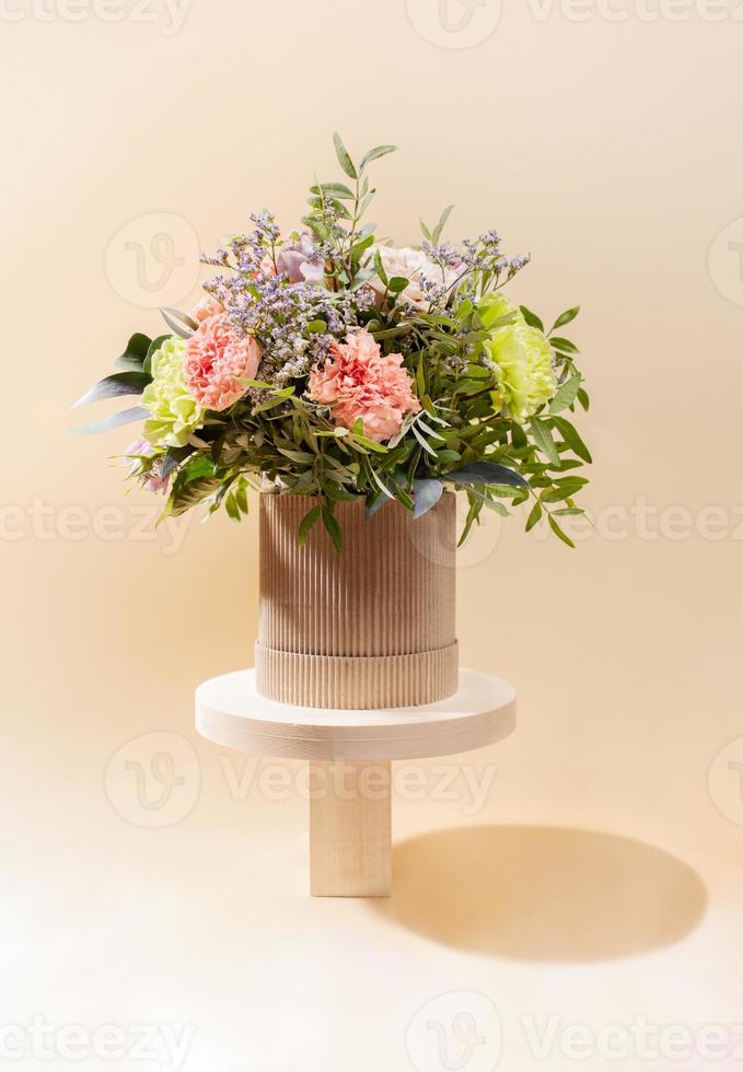 eco vriendelijk monochroom samenstelling met bloemen boeket staand Aan houten staat van verschillend vormen Aan beige. foto