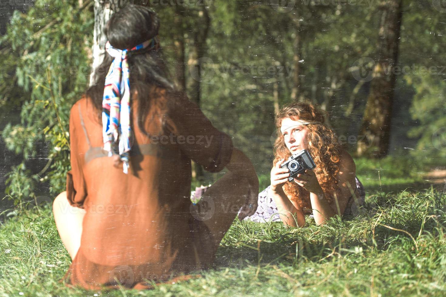 mooi vrij hippie meisjes Aan de gras nemen foto's met een oud - wijnoogst effect foto