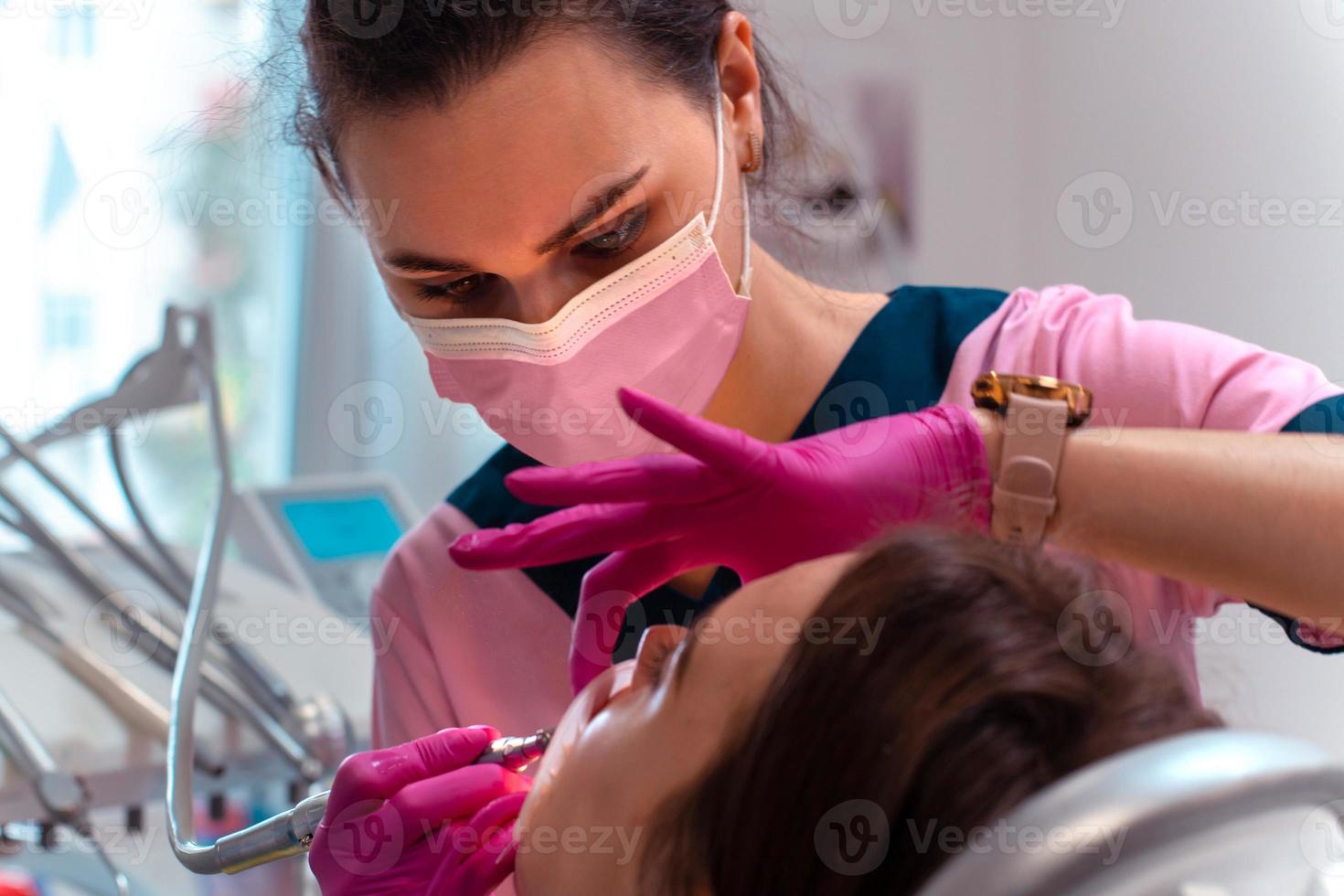 tandarts in roze uniform traktatie de tanden van een geduldig foto