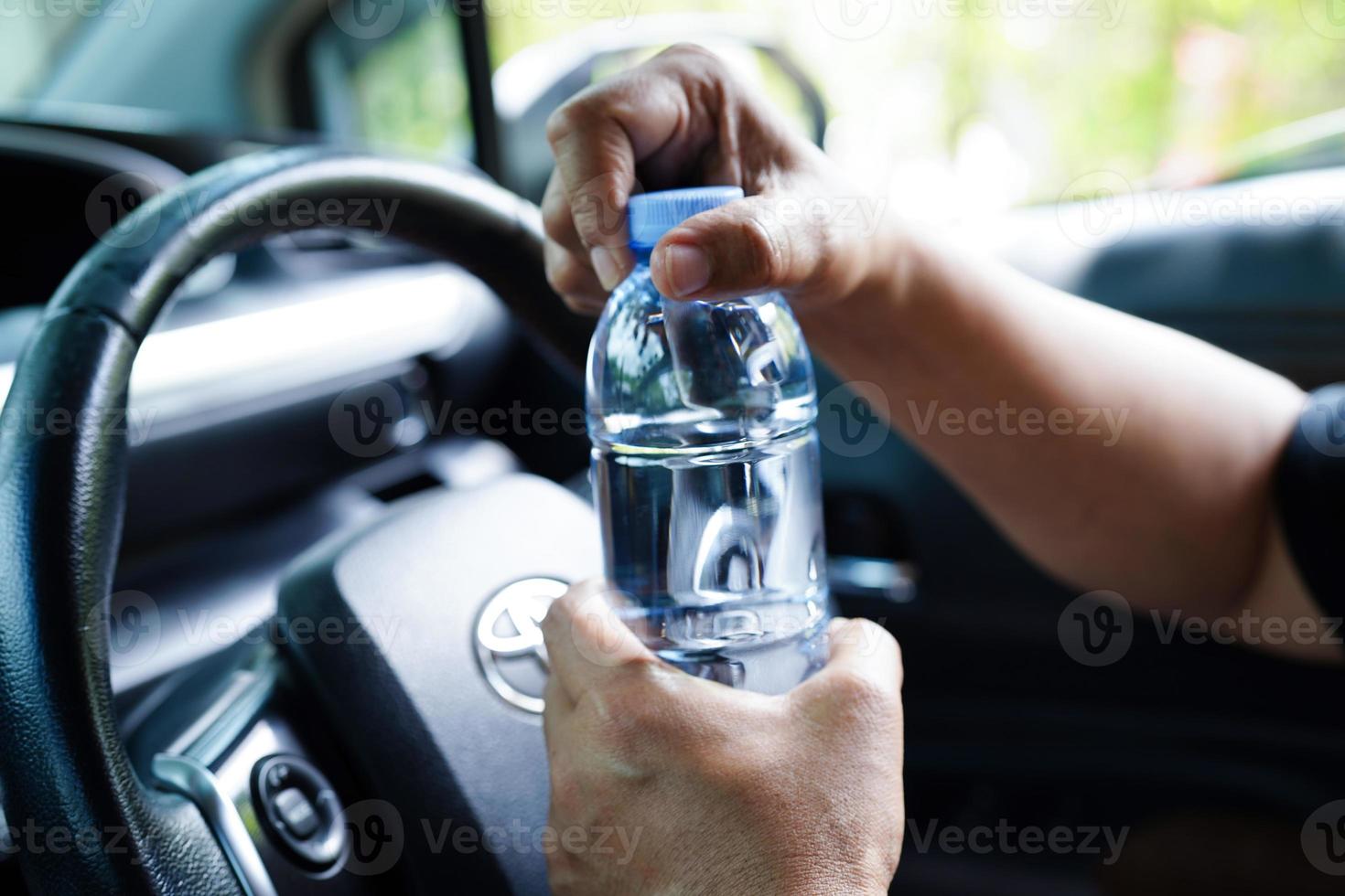 Bangkok, Thailand - mei 15, 2022 Aziatisch vrouw bestuurder houden verkoudheid water voor drinken in auto, gevaarlijk en risico een ongeluk. foto