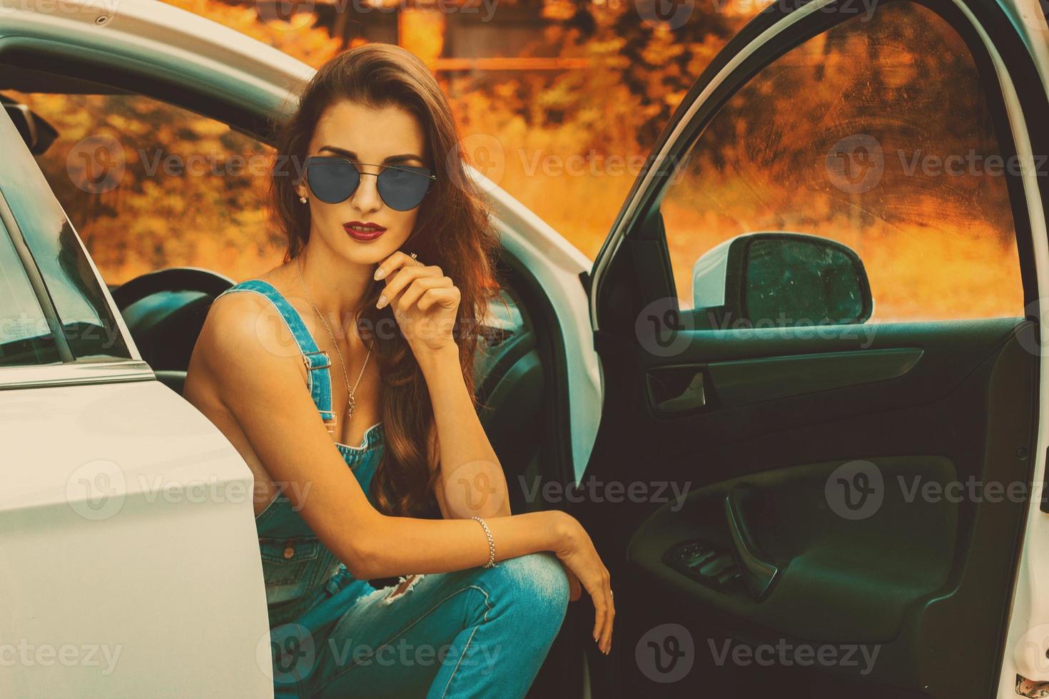 jong brunette in blauw zonnebril in de auto foto