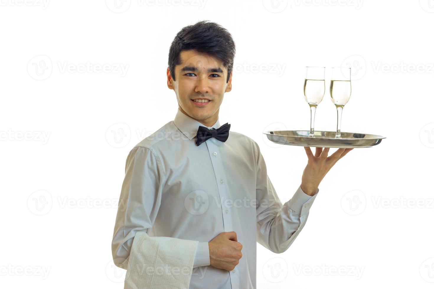 aantrekkelijk jong ober verheven zijn hand- dienblad met twee bril en glimlachen foto