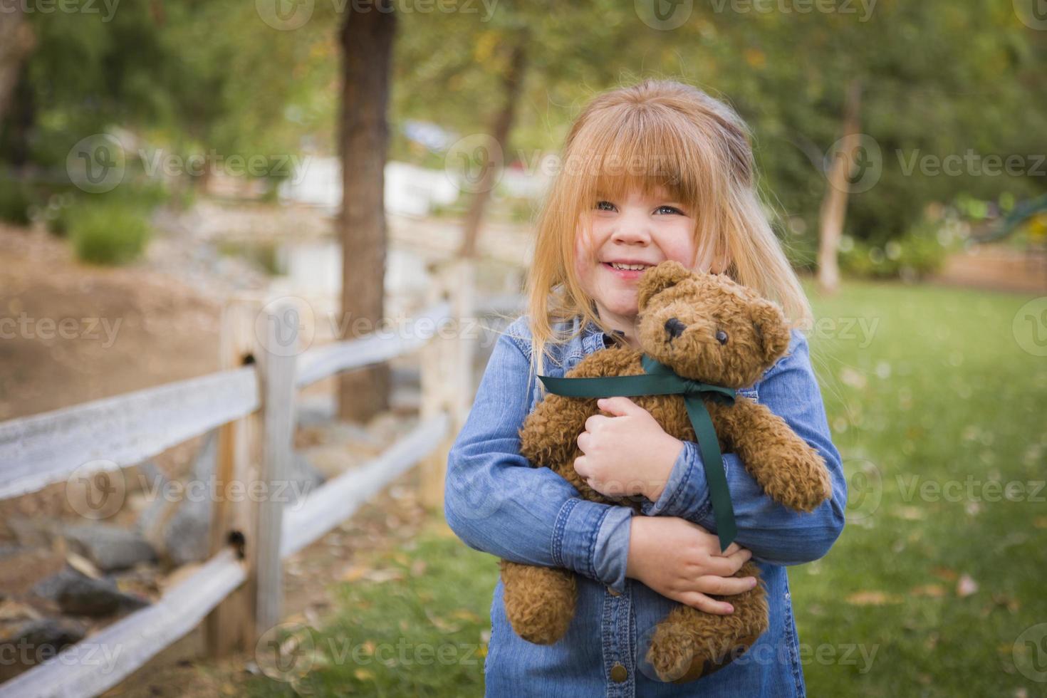 schattig glimlachen jong meisje knuffelen haar teddy beer buiten foto