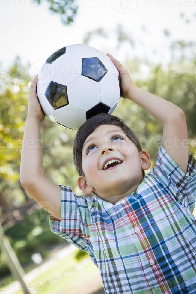 schattige jonge jongen spelen met voetbal in park foto