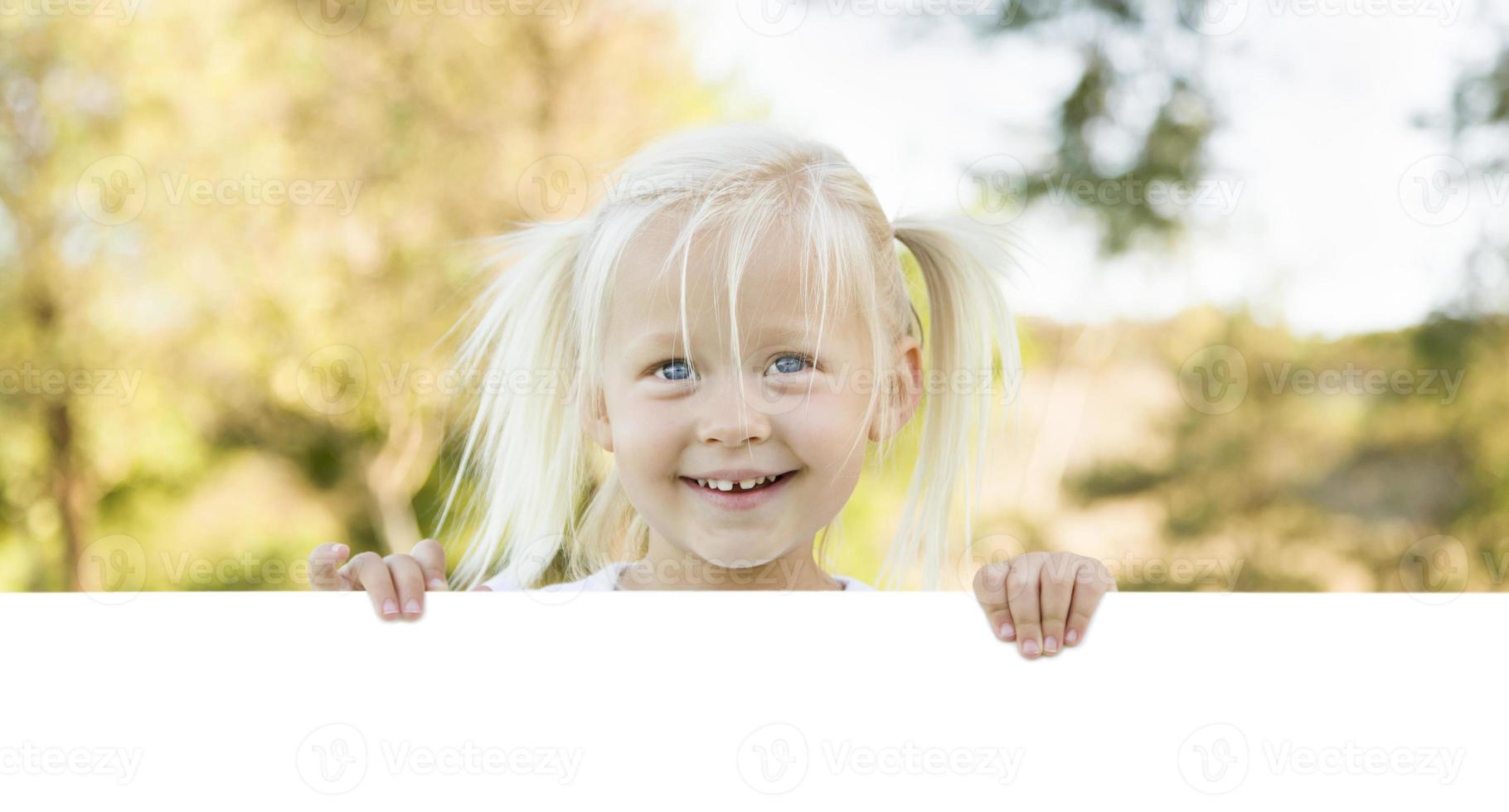 schattig weinig meisje Holding wit bord met kamer voor tekst foto