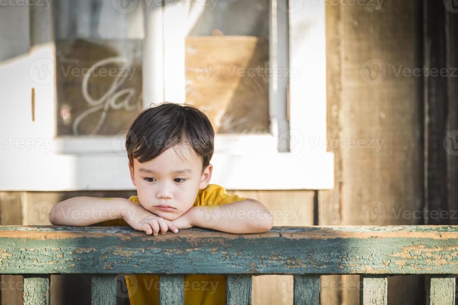 melancholie gemengd ras jongen leunend Aan traliewerk foto