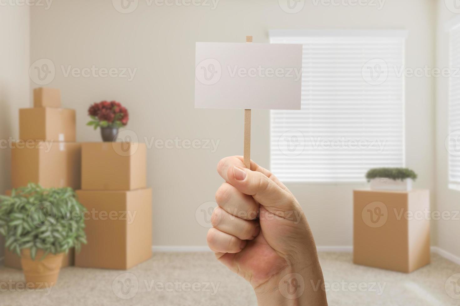 hand- Holding blanco teken in leeg kamer met Ingepakt in beweging dozen foto