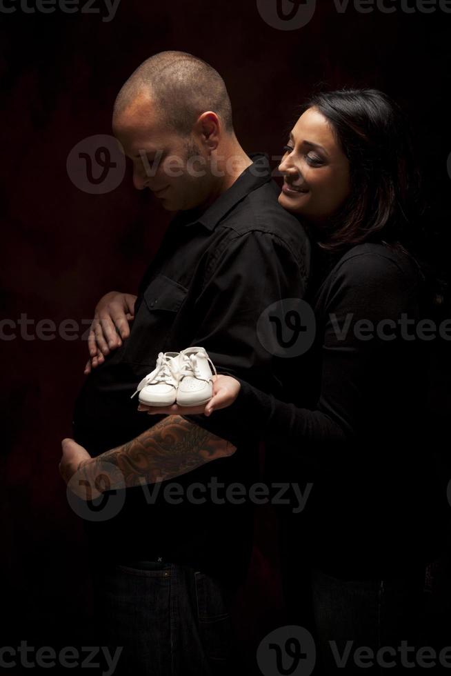 gemengd ras paar Holding nieuw wit baby schoenen Aan zwart foto
