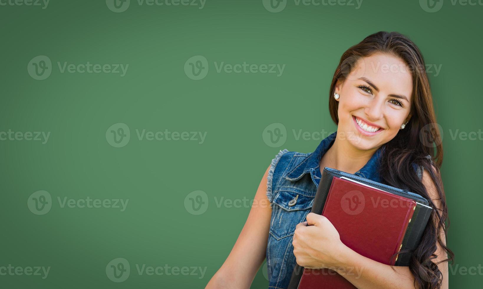 blanco krijt bord achter gemengd ras jong meisje leerling Holding boeken foto