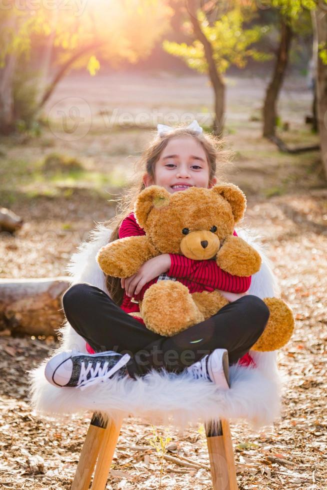 schattig jong gemengd ras meisje knuffelen teddy beer buitenshuis foto