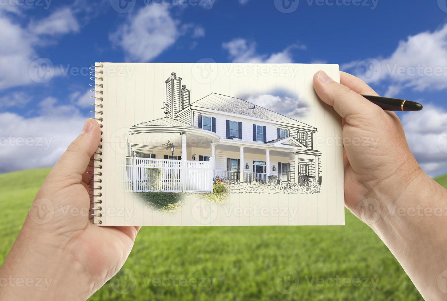 handen Holding papier met huis tekening over- leeg gras veld- foto