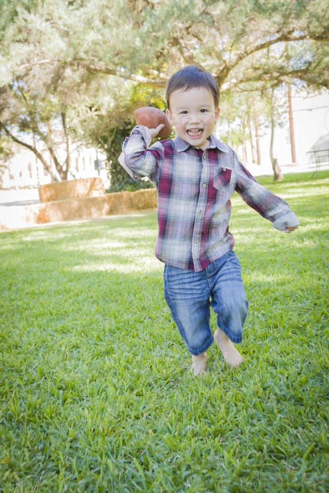 schattig jong gemengd ras jongen spelen Amerikaans voetbal buiten foto