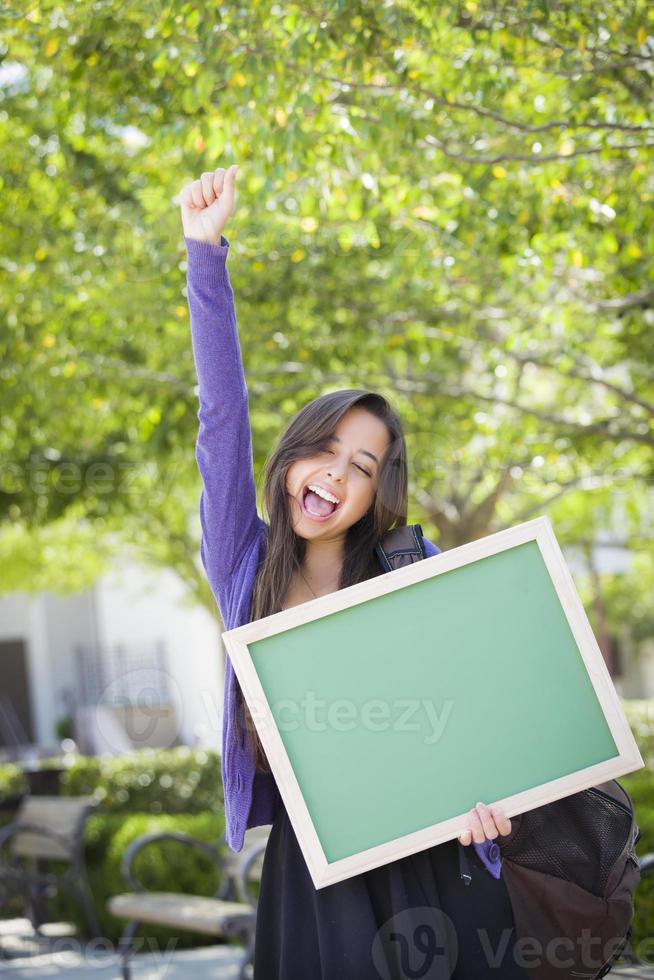 opgewonden gemengd ras vrouw leerling Holding blanco schoolbord foto