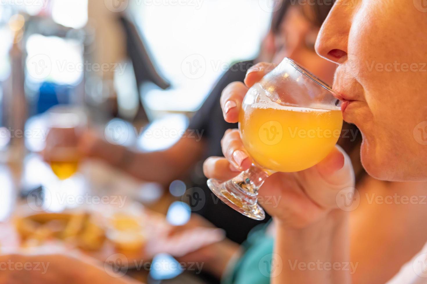 vrouw nippen glas van micro brouwen bier Bij bar met vrienden foto