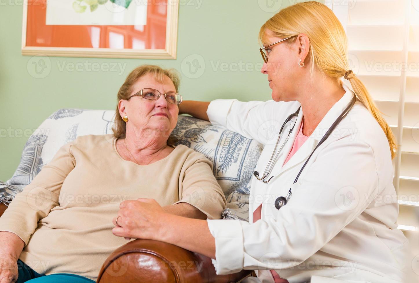 gelukkig glimlachen dokter of verpleegster pratend naar senior vrouw in stoel Bij huis foto