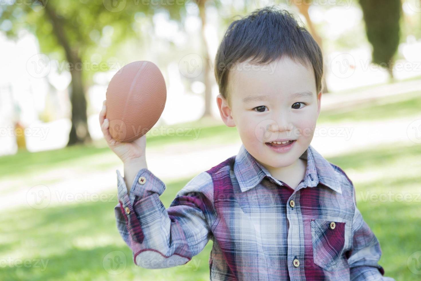 schattig jong gemengd ras jongen spelen Amerikaans voetbal buiten foto