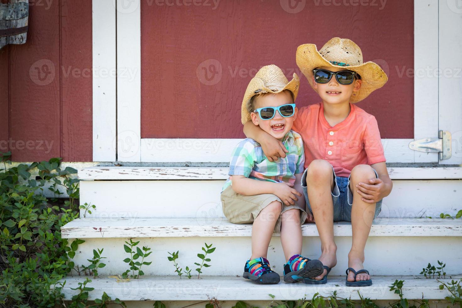 gemengd ras Chinese en Kaukasisch jong broers hebben pret vervelend zonnebril en cowboy hoeden foto