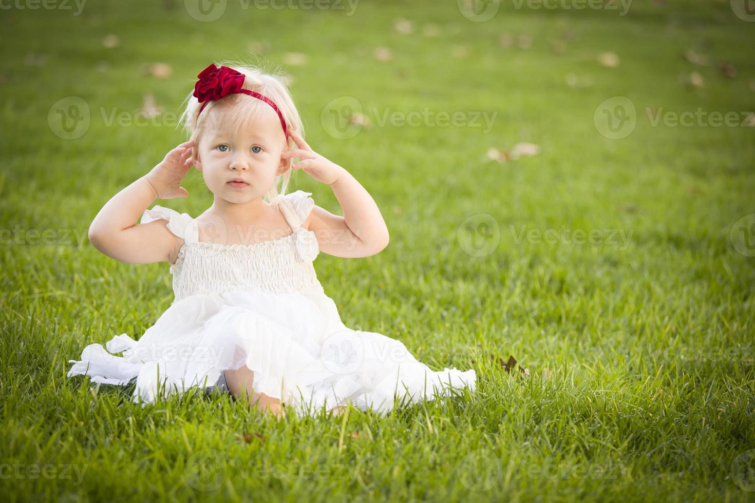 aanbiddelijk weinig meisje vervelend wit jurk in een gras veld- foto