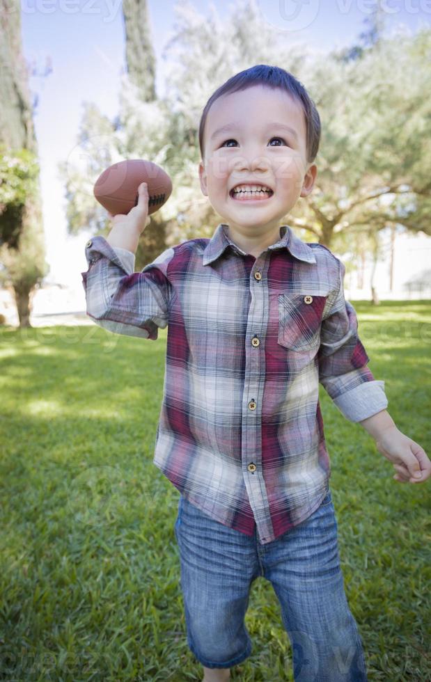 schattig jong gemengd ras jongen spelen Amerikaans voetbal buiten foto