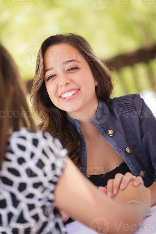 twee gemengd ras vriendinnetjes hebben een gesprek Bij een buiten patio tafel foto