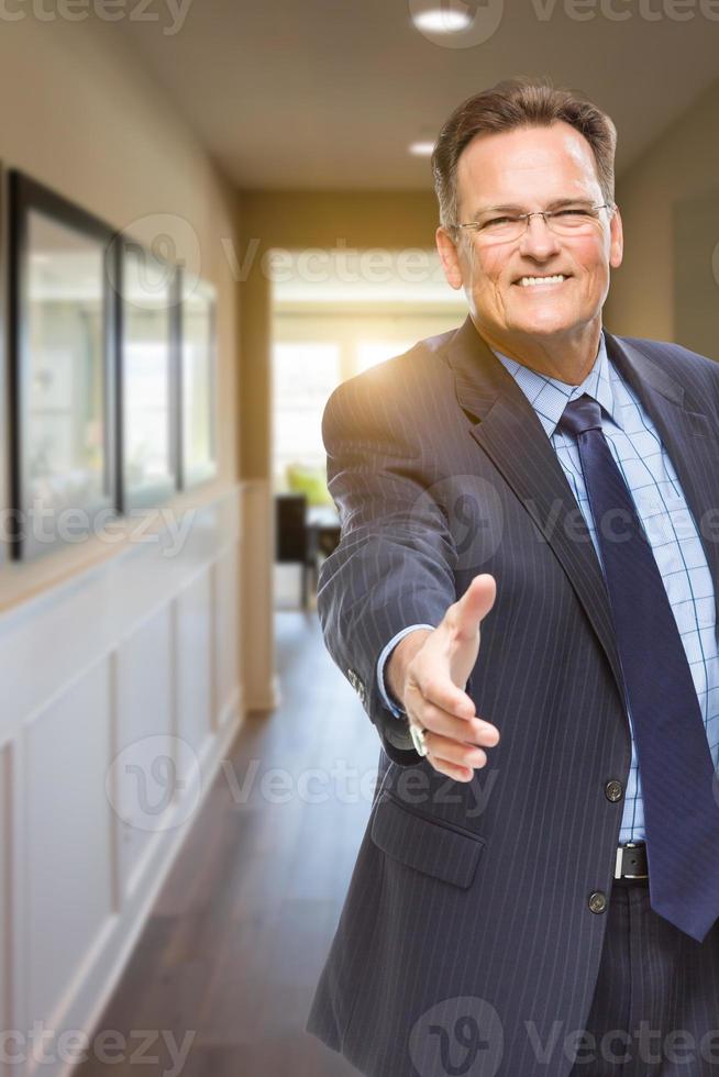 mannetje middel bereiken voor hand- schudden in gang van huis foto