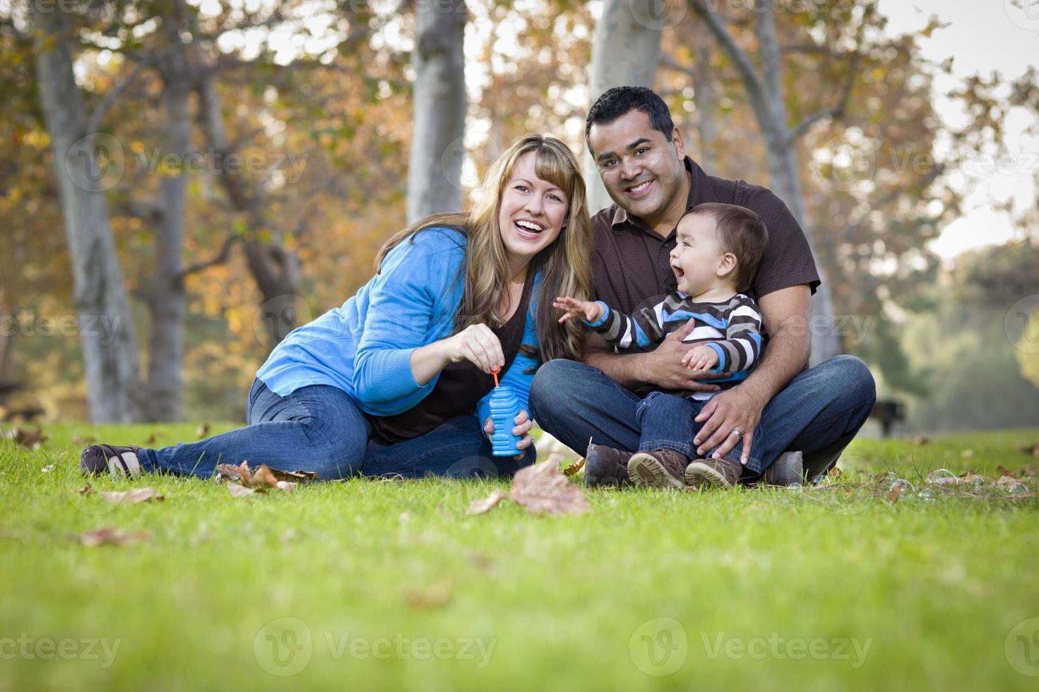 gelukkig gemengd ras etnisch familie spelen met bubbels in de park foto