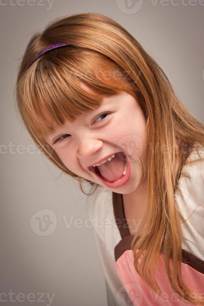 pret portret van een aanbiddelijk rood haren meisje Aan grijs foto