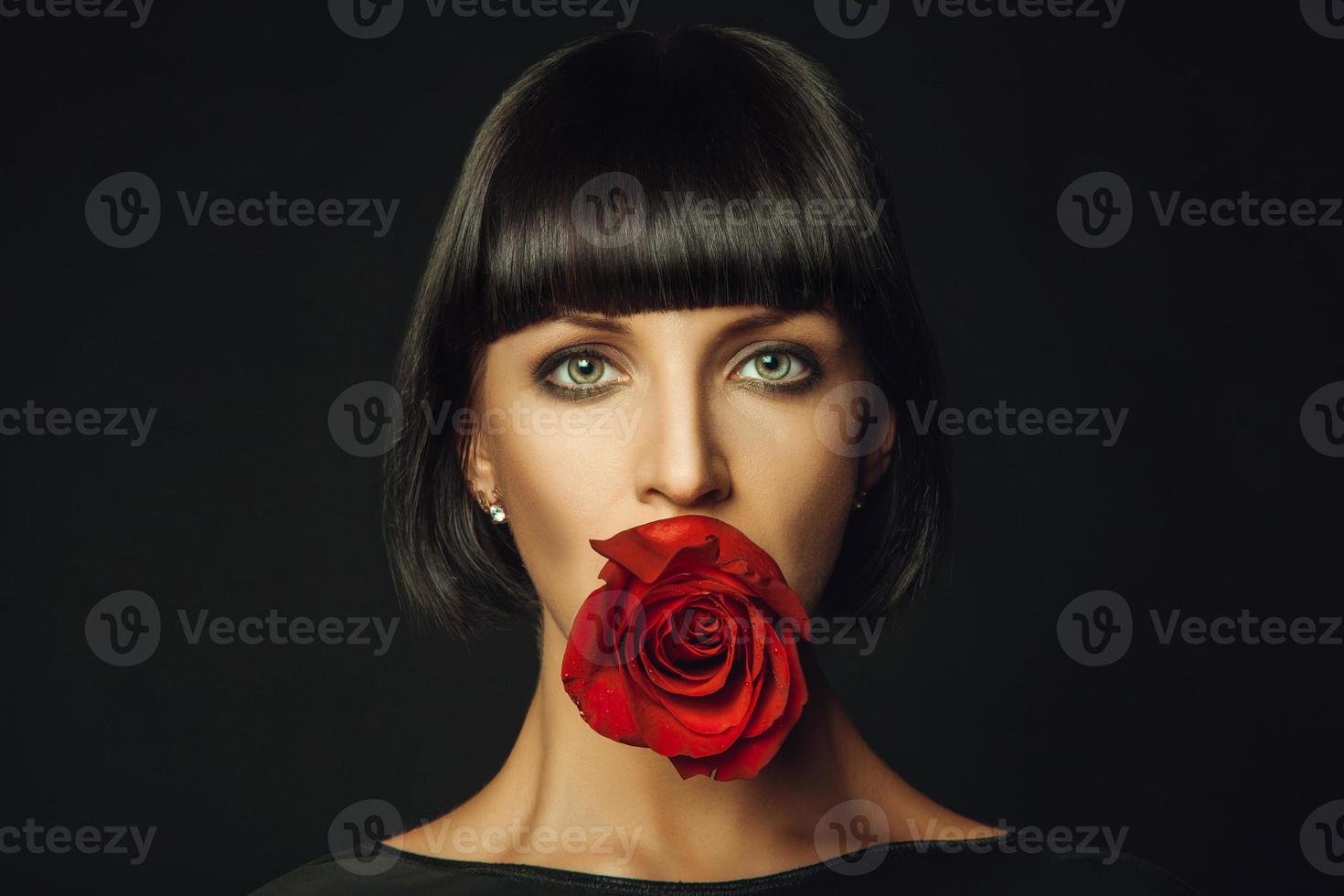 volwassen vrouw met rood roos in mond foto