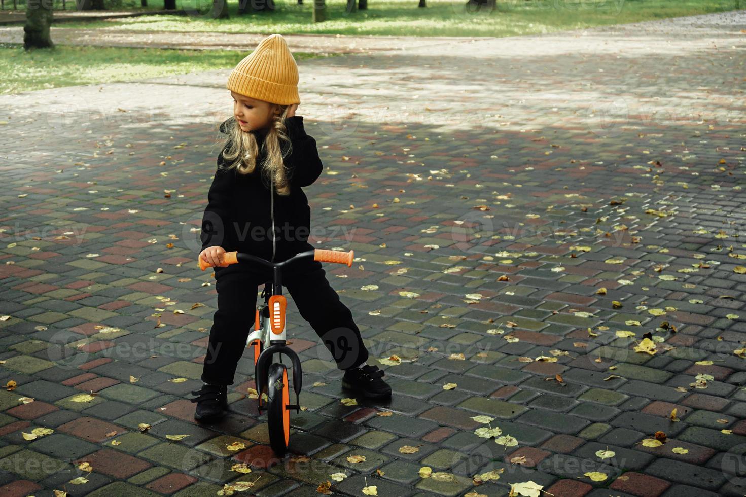 schattig weinig meisje ritten Aan fiets Bij de park foto