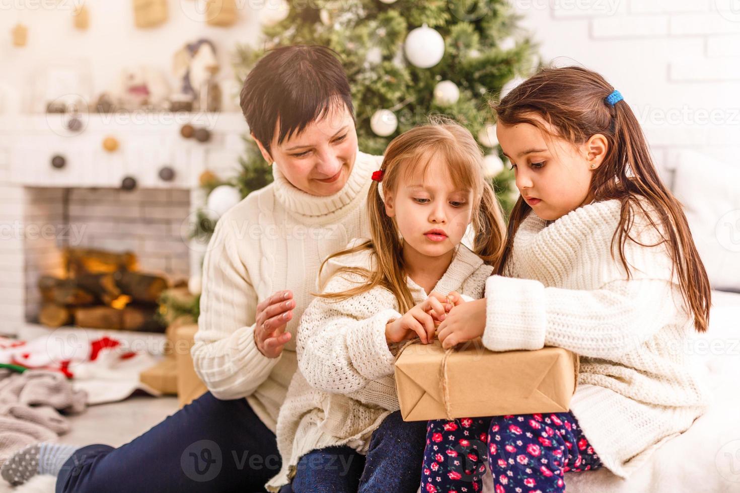 kinderen weinig zussen houden cadeaus dozen interieur achtergrond. wat een Super goed verrassing. klein schattig meisjes ontvangen vakantie geschenken. het beste speelgoed en Kerstmis geschenken. kinderen vrienden opgewonden uitpakken hun geschenken. foto